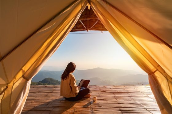 Remote worker with laptop and tablet at outdoor garden desk showing digital nomad lifestyle and location independence for global professionals seeking residency