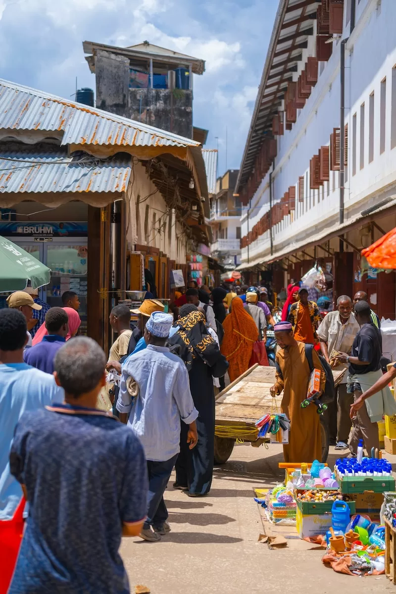 A bustling scene at Darajani Market in Stone Town, with vendors selling fresh produce and spices under colorful tarps, capturing the heart of local trade.