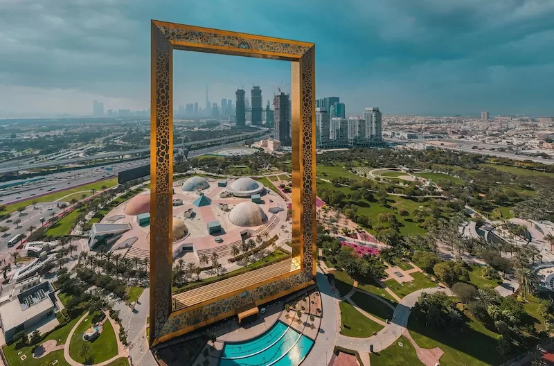 The massive Dubai Frame stands tall in Zabeel Park, framing the distant city skyline of Dubai, United Arab Emirates, symbolizing a modern global business hub.