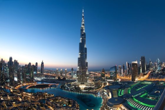 Burj Khalifa towering above the illuminated Dubai skyline at dusk with surrounding skyscrapers and fountains.