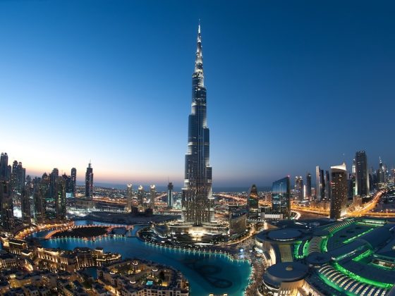 Burj Khalifa towering above the illuminated Dubai skyline at dusk with surrounding skyscrapers and fountains.