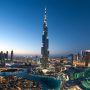 Burj Khalifa towering above the illuminated Dubai skyline at dusk with surrounding skyscrapers and fountains.