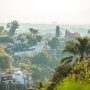 Hillside neighborhood in Mexico with white villas, palm trees, and lush vegetation overlooking the city