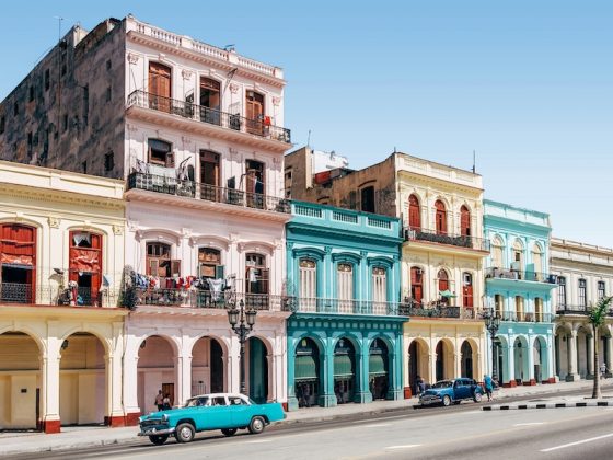 Colorful colonial buildings and classic cars lining a historic street in Havana, Cuba.