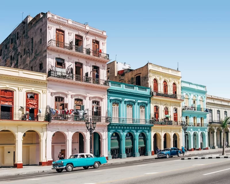 Colorful colonial buildings and classic cars lining a historic street in Havana, Cuba.