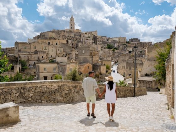 Couple walking through historic European old town with stone buildings and hillside architecture in Southern Europe