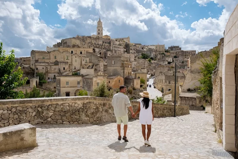 Couple walking through historic European old town with stone buildings and hillside architecture in Southern Europe