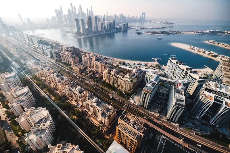 Aerial view of Dubai Marina and Palm Jumeirah with modern skyscrapers, waterfront developments, and coastal skyline.