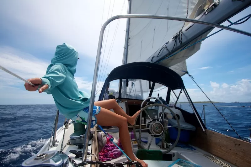 Solo sailor relaxing on sailboat deck looking toward the open ocean horizon