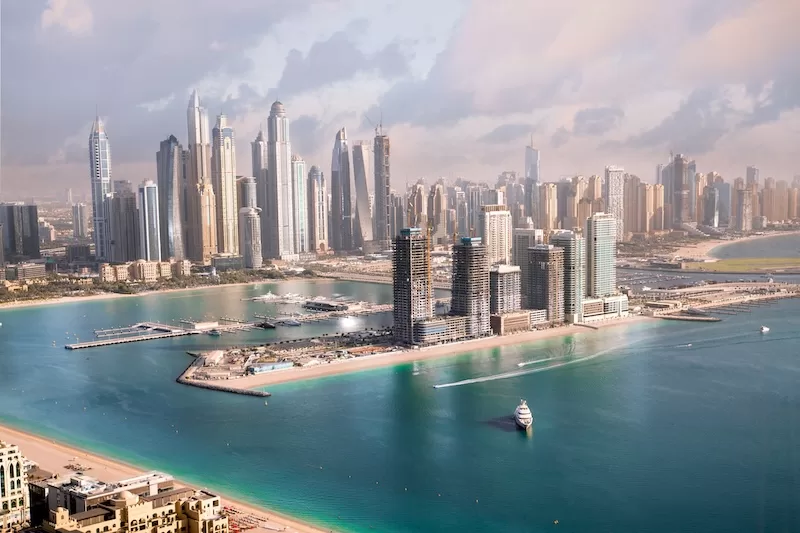 Aerial view of Dubai’s Palm Jumeirah and marina skyline with luxury high-rise buildings and turquoise waterfront.