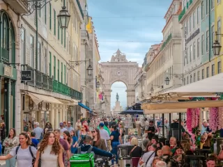 Busy pedestrian street in Lisbon with shops cafes and Arco da Rua Augusta in the background