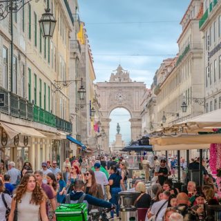 Busy pedestrian street in Lisbon with shops cafes and Arco da Rua Augusta in the background