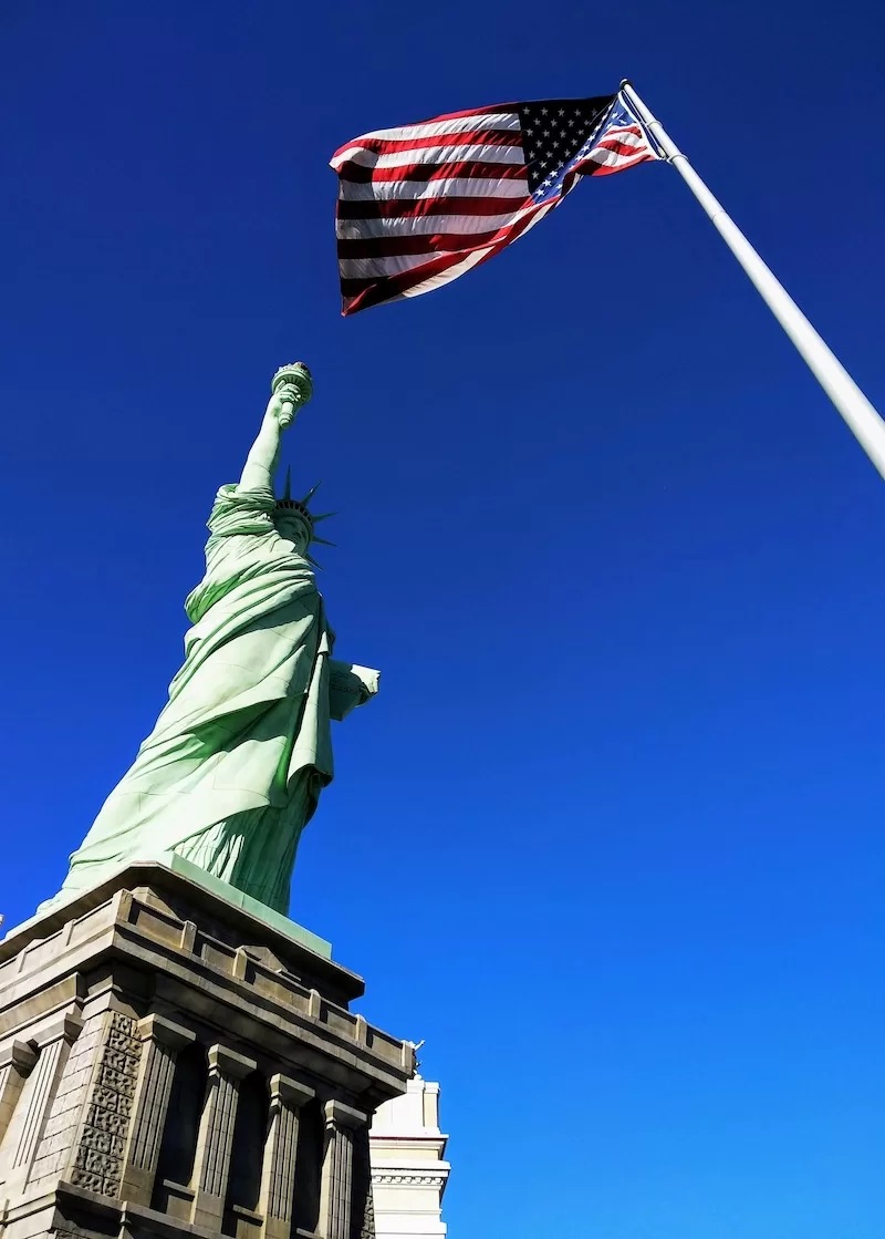 American flag waving on white pole against clear blue sky, symbolizing US migration shift and Americans leaving the country for new opportunities