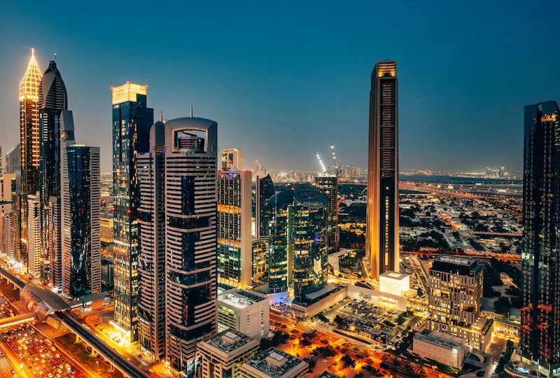 Night skyline of Dubai’s financial district with illuminated skyscrapers and busy urban highways.