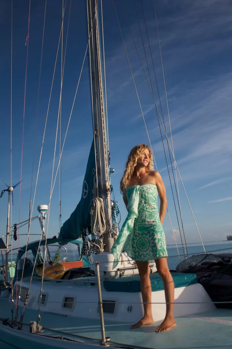 Woman standing on sailboat deck at sunset during a long ocean voyage