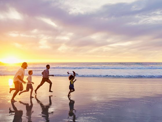 Family of four walking along the beach, representing family-driven approach to starting over abroad