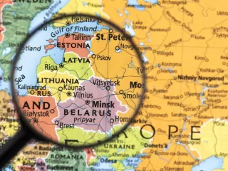 Magnifying glass focused on Estonia and the Baltic region on a printed map of Northern and Eastern Europe.