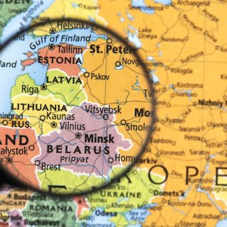 Magnifying glass focused on Estonia and the Baltic region on a printed map of Northern and Eastern Europe.