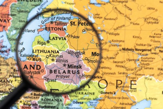 Magnifying glass focused on Estonia and the Baltic region on a printed map of Northern and Eastern Europe.