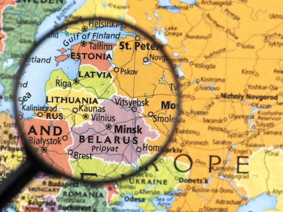 Magnifying glass focused on Estonia and the Baltic region on a printed map of Northern and Eastern Europe.
