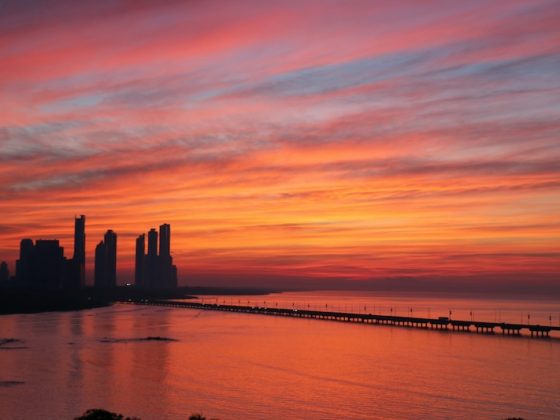 Panama City skyline silhouetted against a vivid sunset over the Pacific coast.