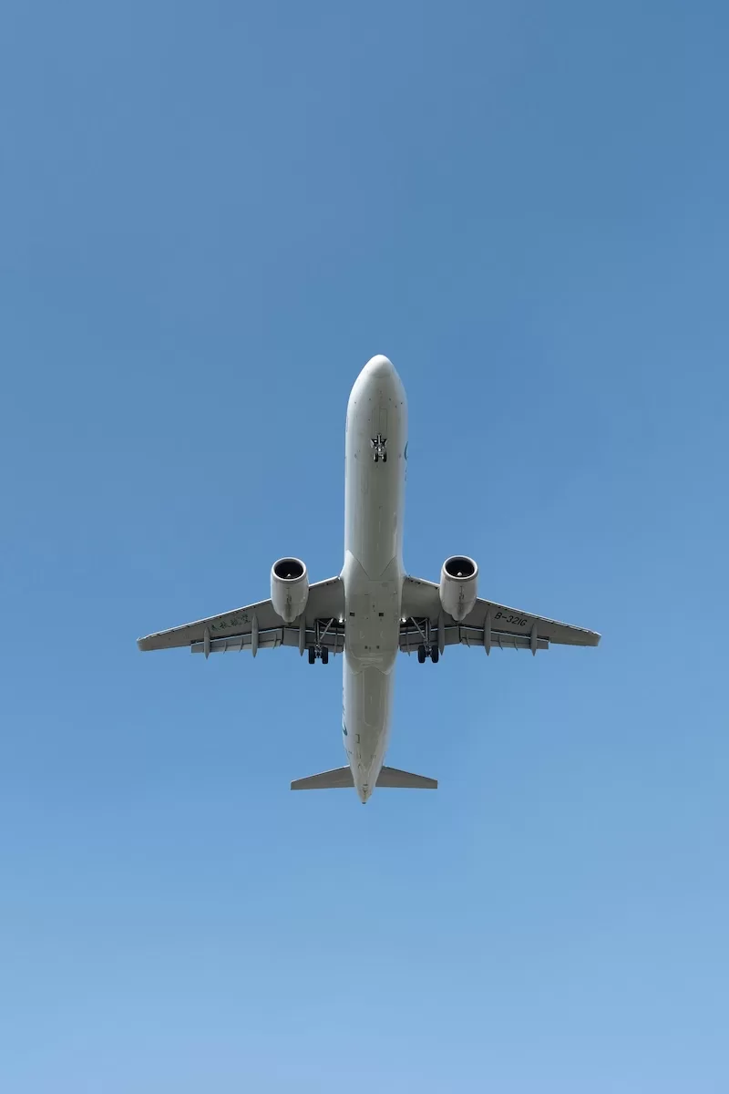 Commercial airplane viewed from below in a clear blue sky with landing gear visible