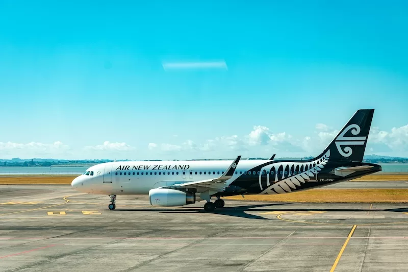 Air New Zealand aircraft parked on an airport runway beneath a clear blue sky
