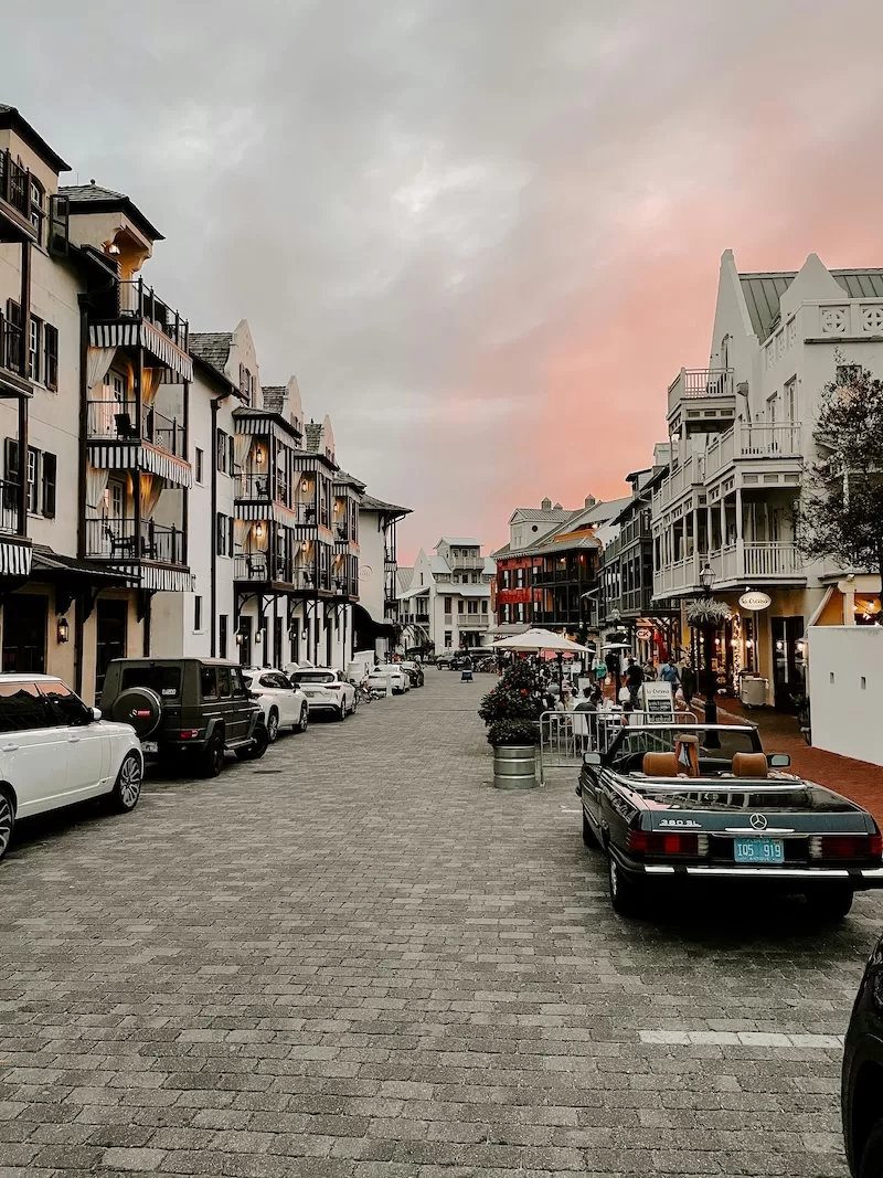 Walkable cobblestone street in a stylish Panama neighborhood lined with shops, balconies, and parked cars at dusk.