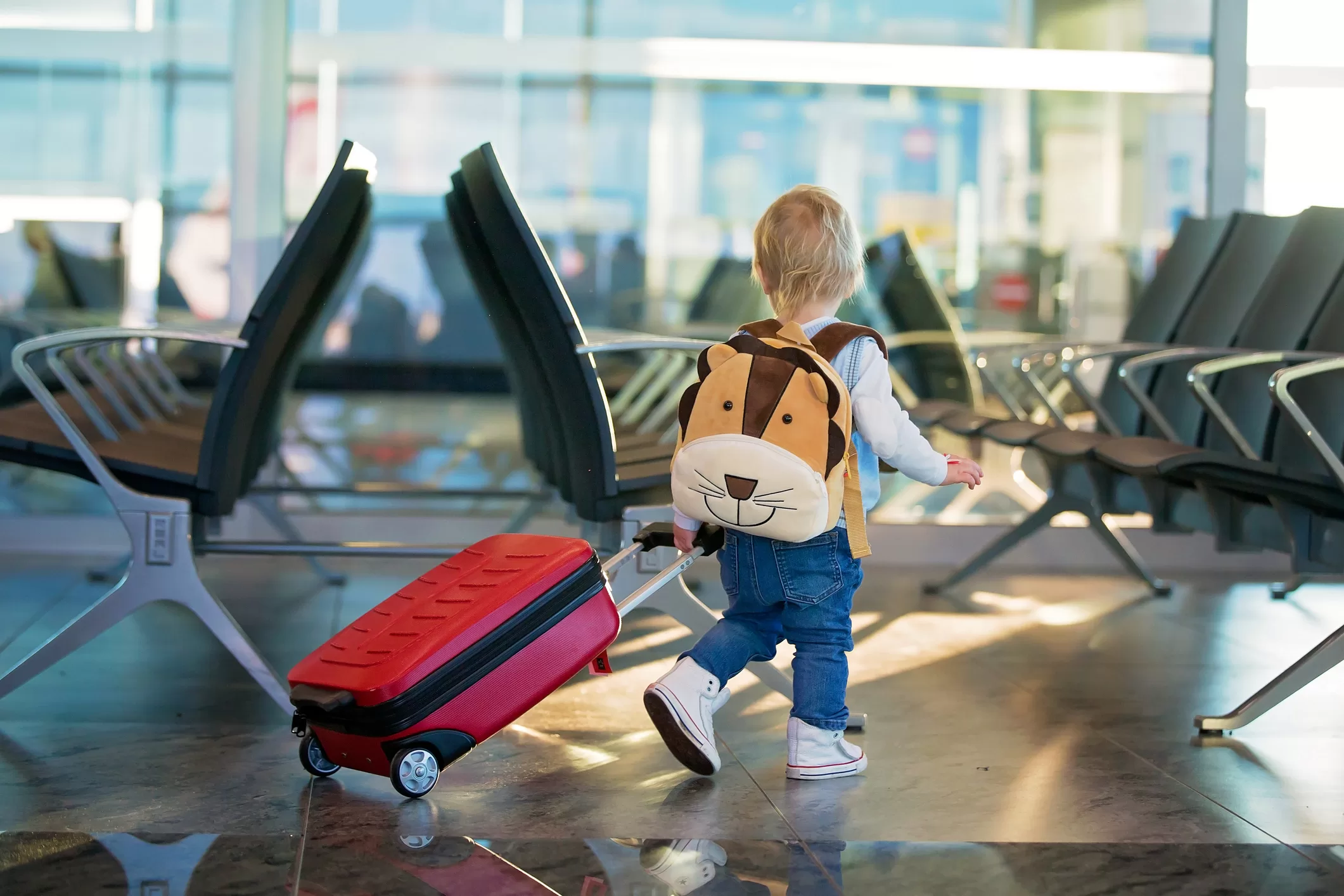 Young child walking through an airport with a suitcase, representing international school transitions and family relocation abroad.