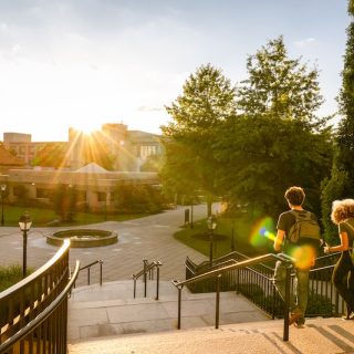 Two students walking across a university campus at sunset, representing international schooling, higher education, and study abroad opportunities.