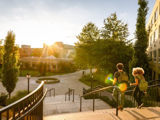 Two students walking across a university campus at sunset, representing international schooling, higher education, and study abroad opportunities.