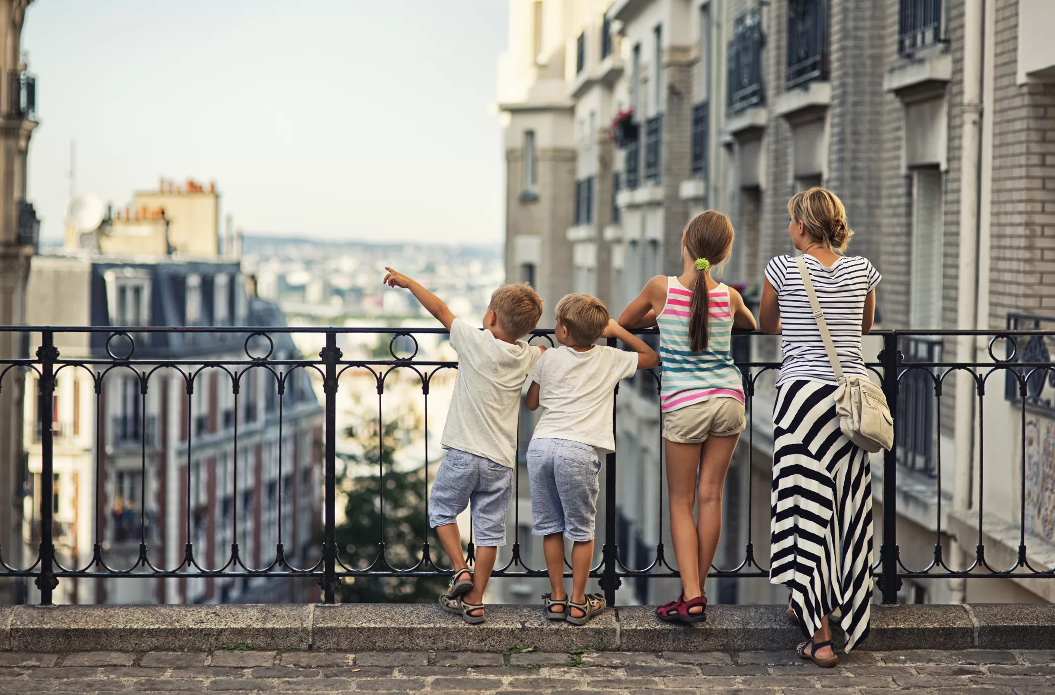Mother and children overlooking a European city neighborhood, representing family relocation and international schooling opportunities abroad.