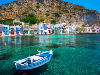 Colorful waterfront village with a blue boat floating in clear turquoise water