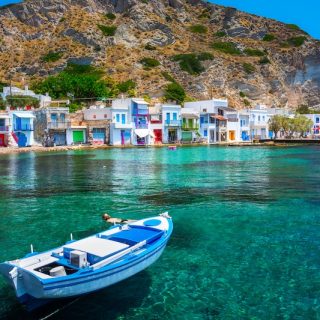 Colorful waterfront village with a blue boat floating in clear turquoise water