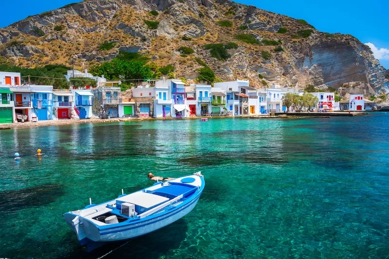 Colorful waterfront village with a blue boat floating in clear turquoise water