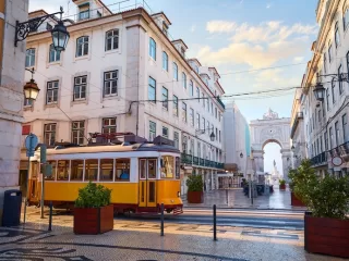 Yellow Lisbon tram passing through a historic street near Rua Augusta Arch.