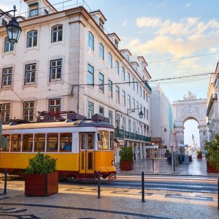 Yellow Lisbon tram passing through a historic street near Rua Augusta Arch.