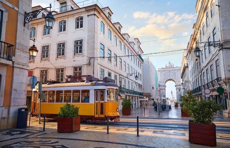 Yellow Lisbon tram passing through a historic street near Rua Augusta Arch.