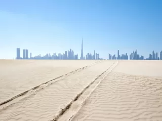 Dubai skyline rising in the distance beyond desert sands