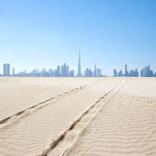 Dubai skyline rising in the distance beyond desert sands