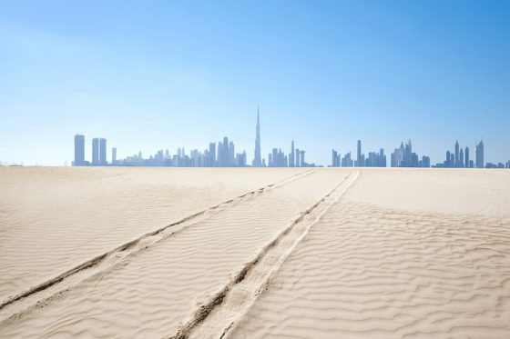Dubai skyline rising in the distance beyond desert sands
