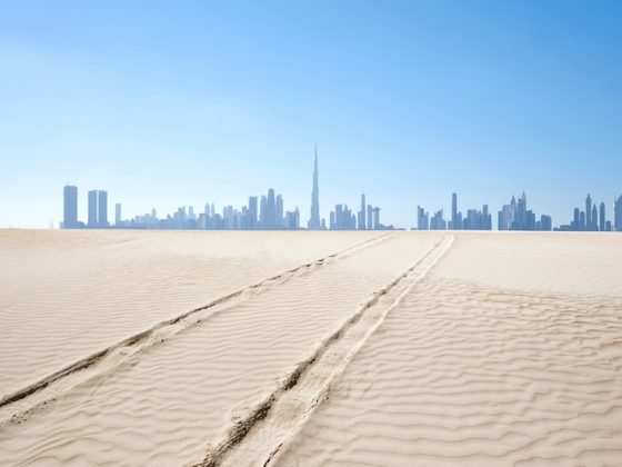 Dubai skyline rising in the distance beyond desert sands