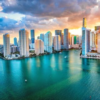 Miami skyline at sunset with high-rise towers and boats on Biscayne Bay