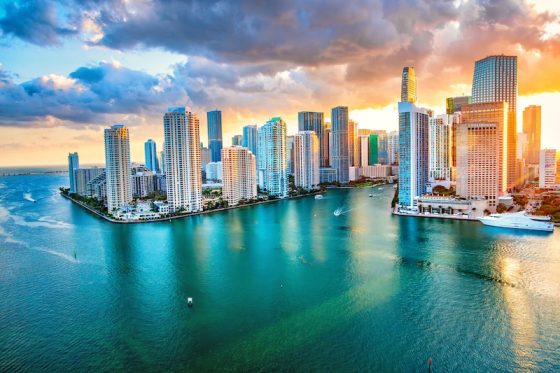 Miami skyline at sunset with high-rise towers and boats on Biscayne Bay
