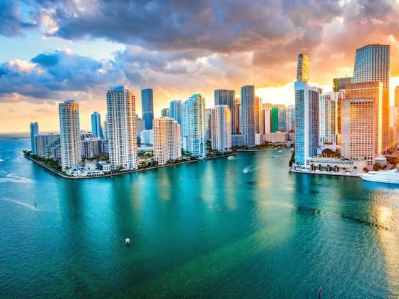 Miami skyline at sunset with high-rise towers and boats on Biscayne Bay