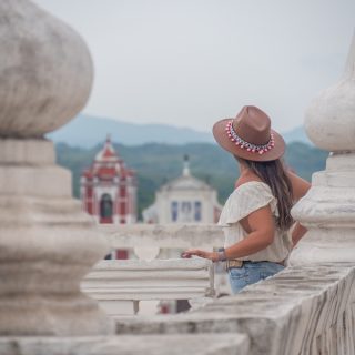 Traveler overlooking a historic Nicaraguan city from a terrace framed by white columns