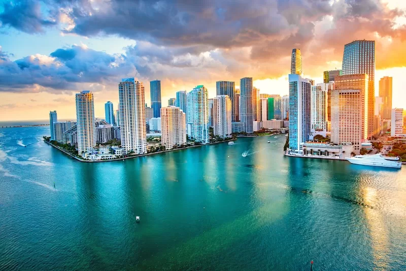 Miami skyline at sunset with high-rise towers and boats on Biscayne Bay