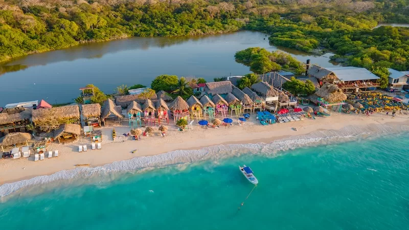 Aerial view of a tropical beach with palm trees, small boats, and white sand