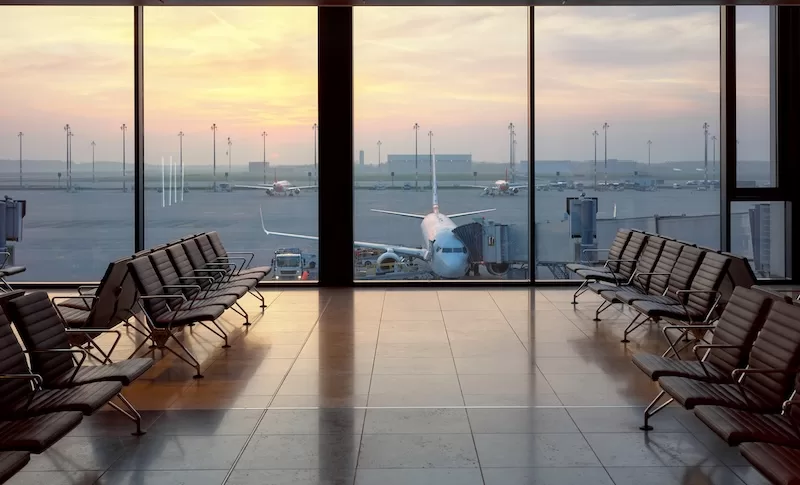 Airport terminal with planes visible through large windows at sunset, representing international travel freedom.