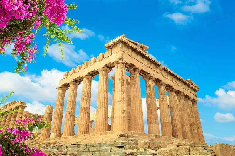 The Parthenon in Athens with bright blue sky and pink flowers